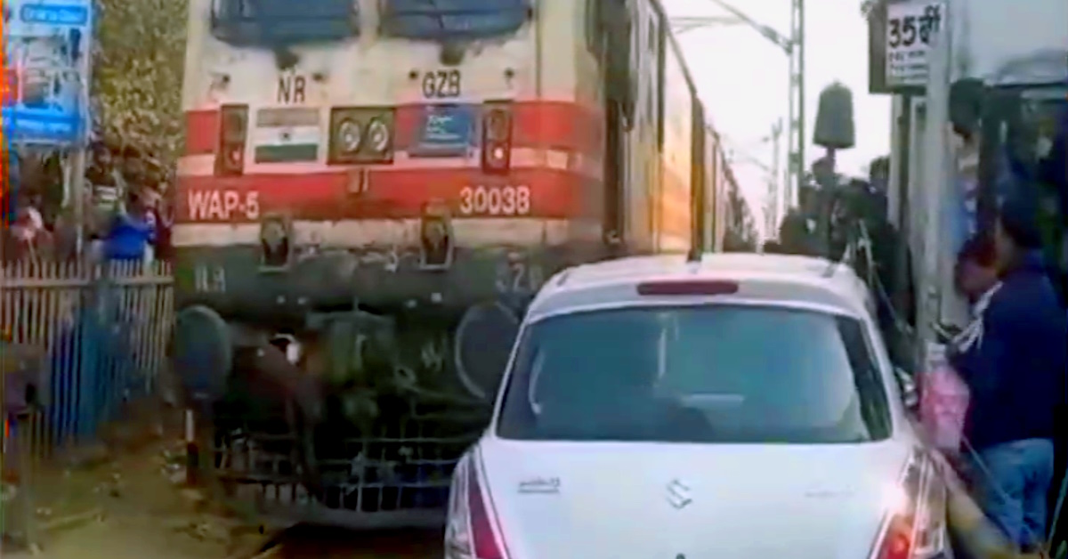 Maruti Swift hatchback car stuck between train and railway gate Maruti Swift hatchback car stuck between train and railway gate